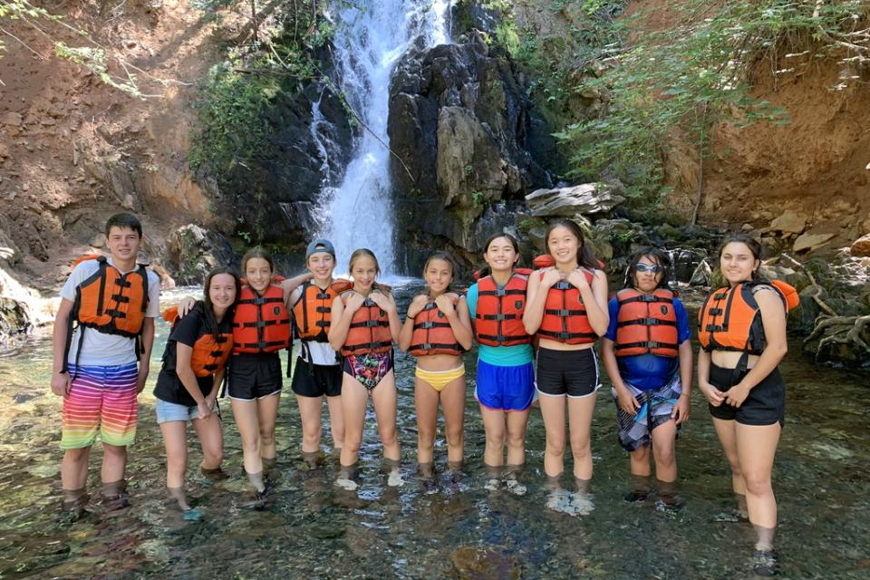 Youth in front of waterfall in the outdoors on a hike at summer camp