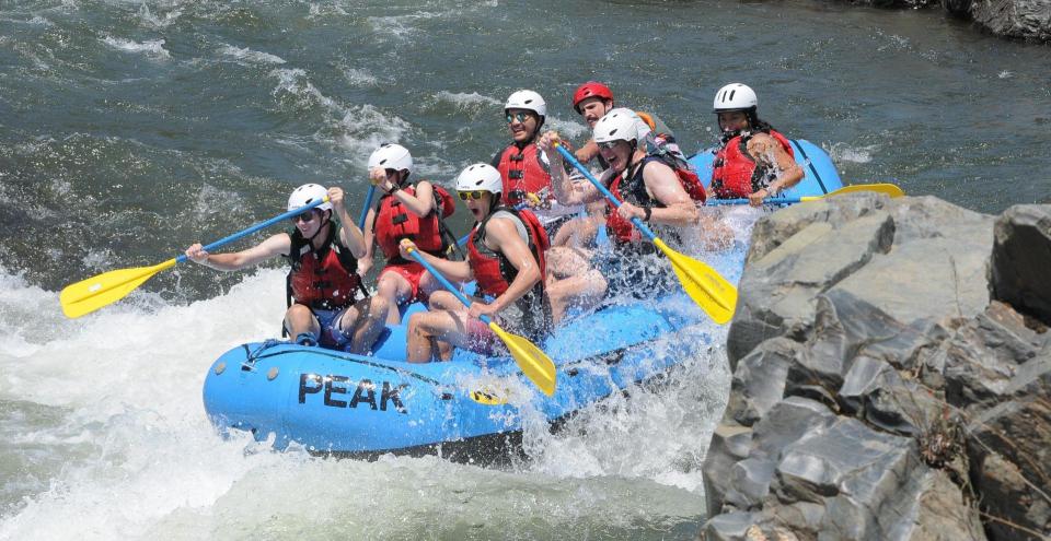 a peak adventures raft navigating rapids on the south fork of the american river.