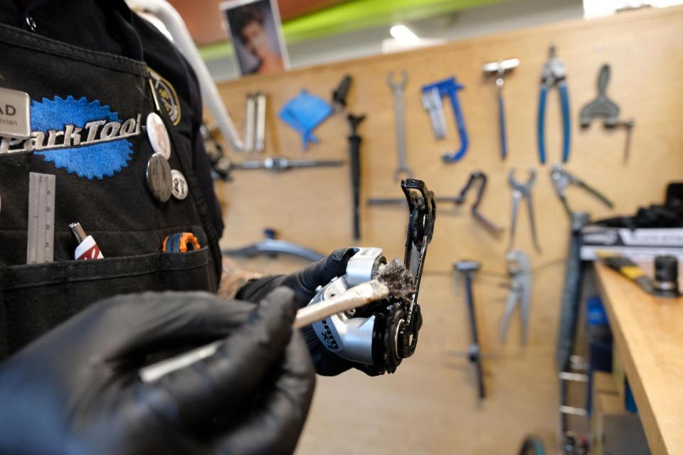 a bike technician greasing a derailleur during a bicycle overhaul