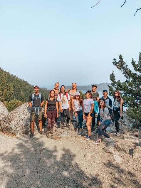 A group of smiling students standing in front of Lake Tahoe on a hike.
