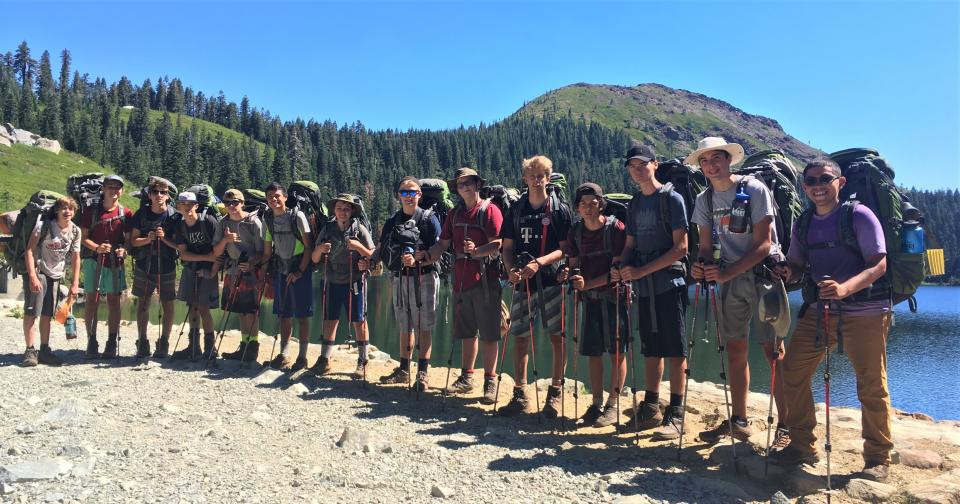 Group of campers about to head out on the trail wearning backpacks.