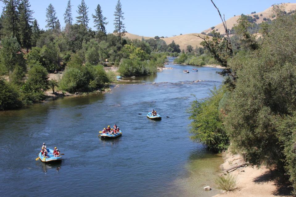an overhead scenic shot of three rafts floating down the south fork of the american river.