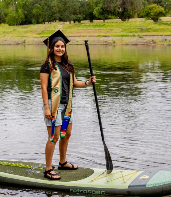 Veronica standing on her paddling wearing her graduation gear