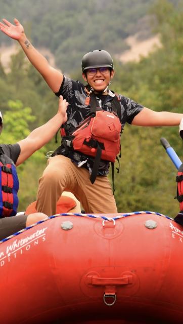 Michael Muñiz smiling on a red raft with a PFD and helmet.